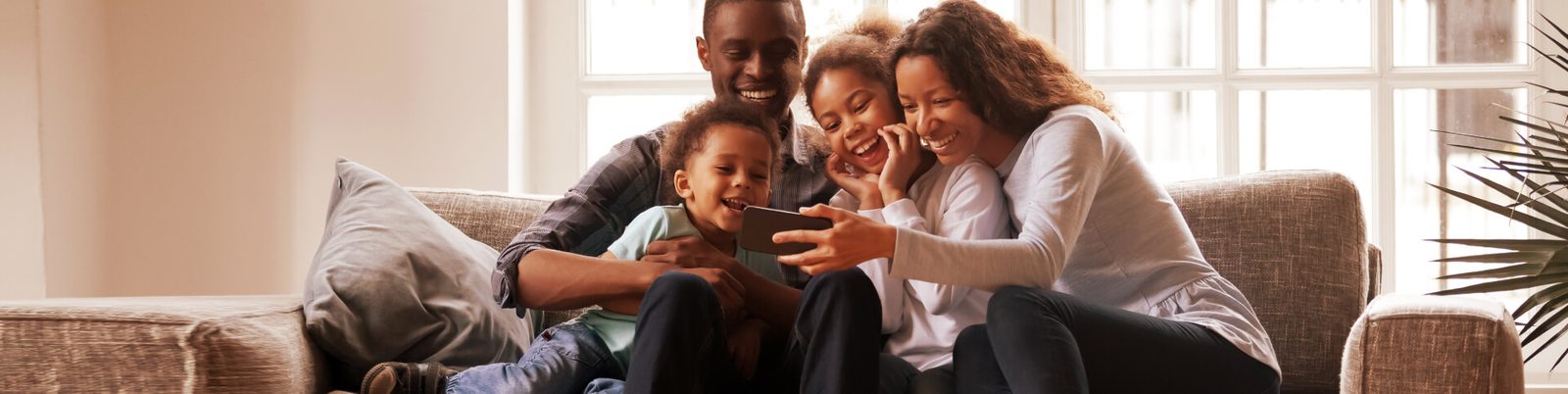 A Kenyan family on a sofa looking at a tablet together