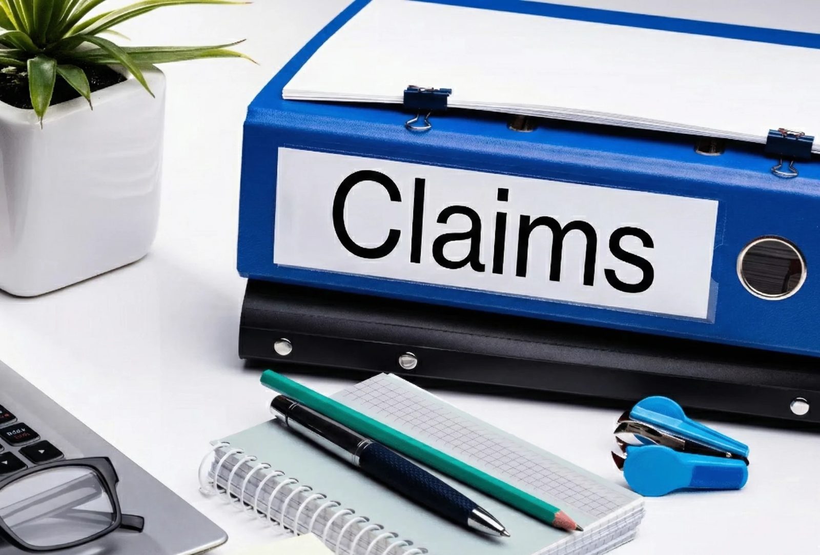 A blue binder labelled Claims on an office desk