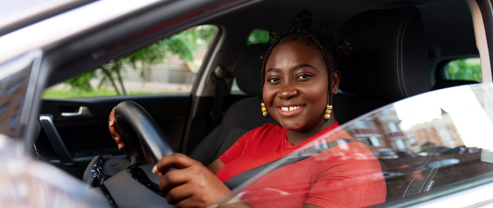 A Kenyan woman smiling at the wheel of her car