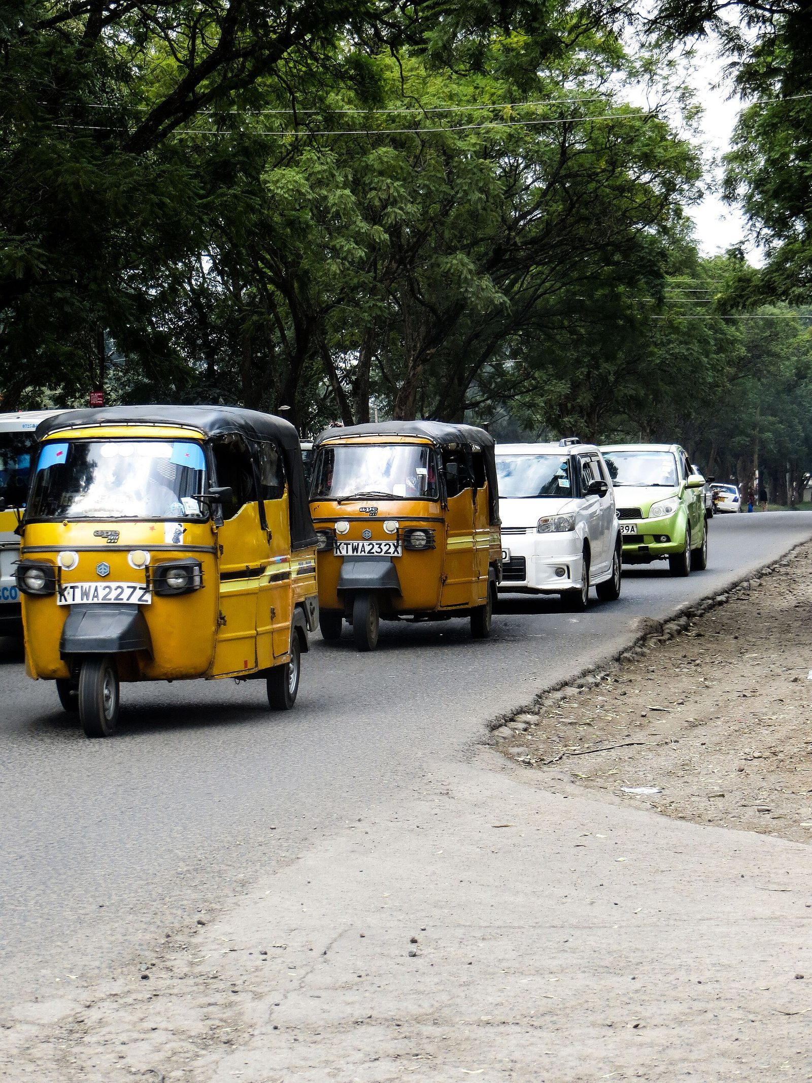 Yellow tuk-tuks in a line on a Kenyan road